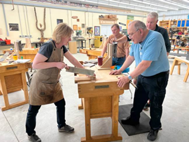 A group of people working in a woodworking workshop  Description automatically generated